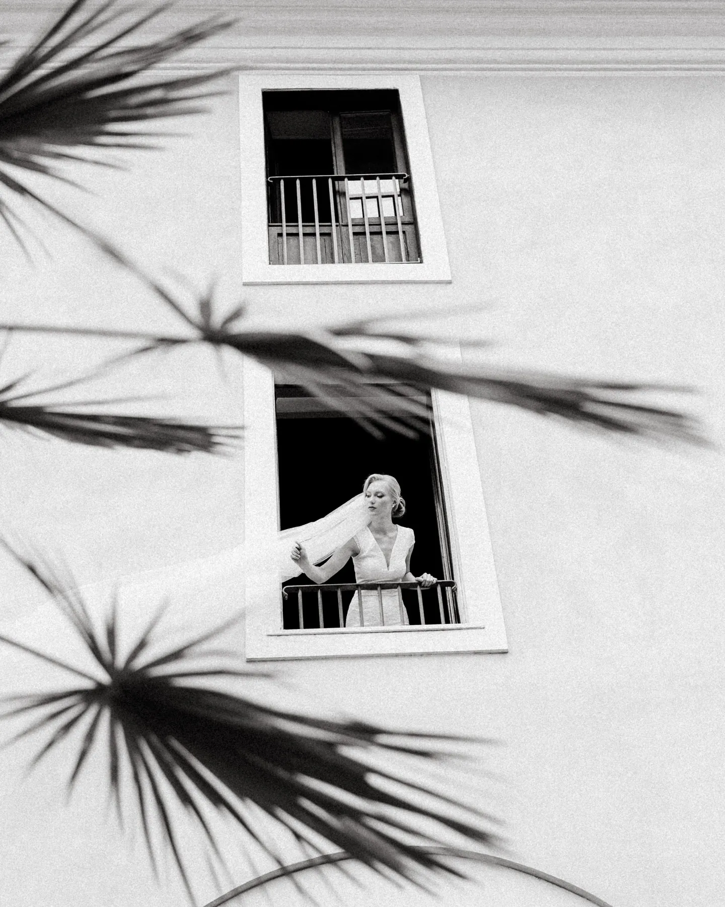 La sposa affacciata alla finestra, fra le ombre delle palme