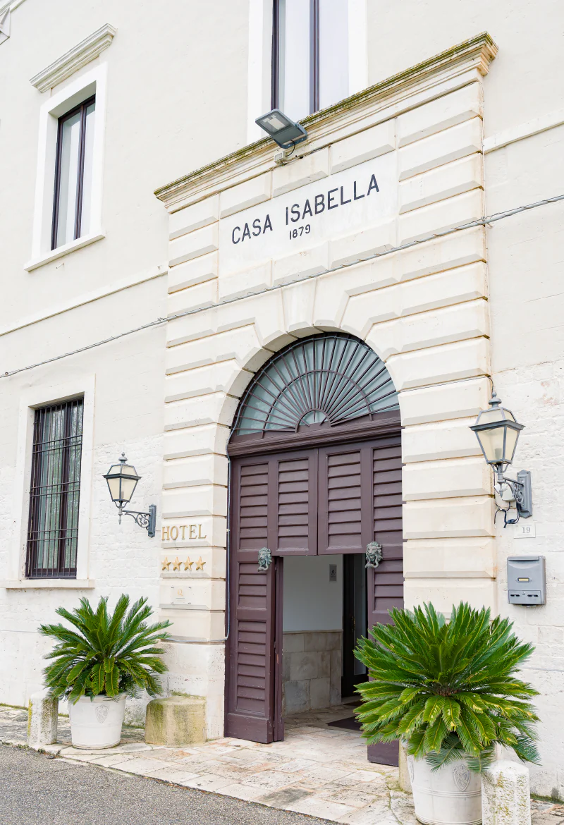 The stone facade of Casa Isabella, with its arched doorway and palms