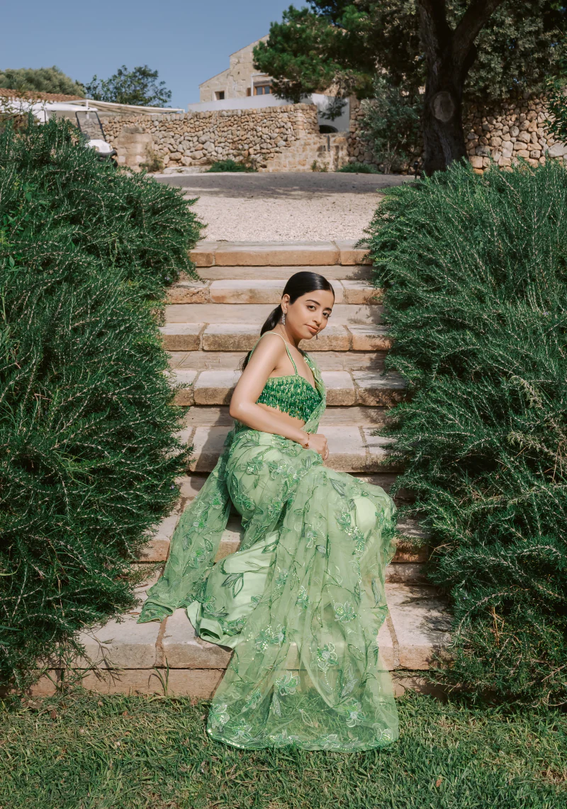 Woman in a green sari seated on garden steps