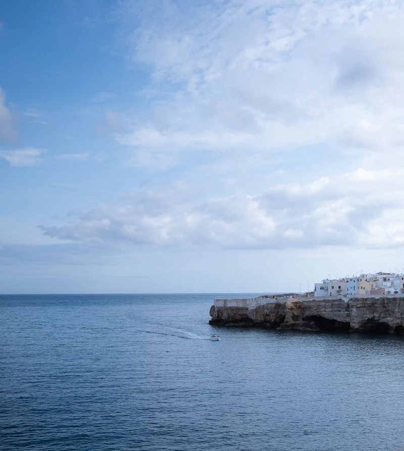 A white town on the cliffs above a calm sea