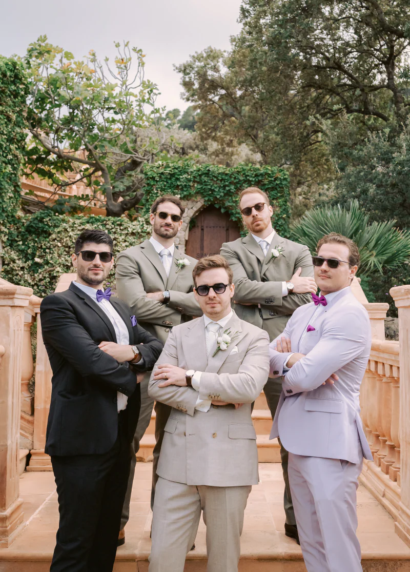Groomsmen in tailored suits and sunglasses on a staircase