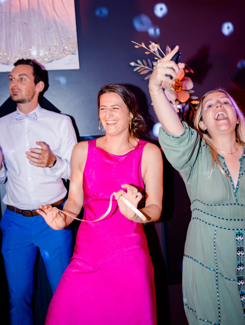 Guests dancing and laughing under coloured lights