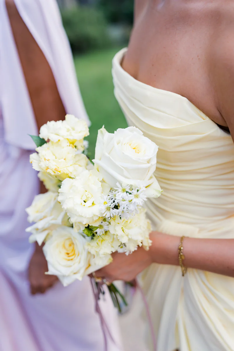 Bridesmaid in a pale yellow dress holding white roses