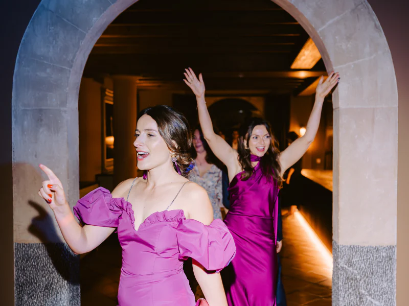 Two guests dancing beneath a stone arch at the party