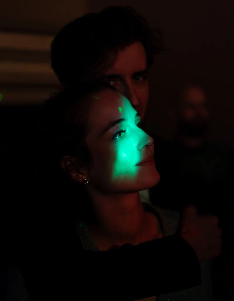 A guest's face lit by a green light at the party